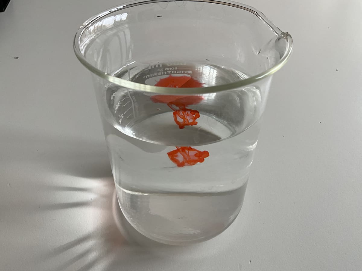 Ein Farbtropfen sinkt als kompakter Klecks ins Wasser